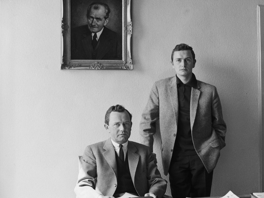 Ferdinand Anton Ernst Porsche behind his office desk and Ferdinand Alexander Porsche standing.
