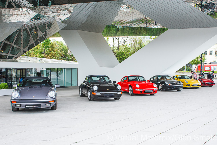Porsche 911s line up outside the entrance to the Porsche Museum