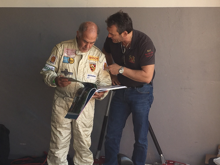 The author hands a copy of the book to well-known Porsche racing driver Willi Kauhsen