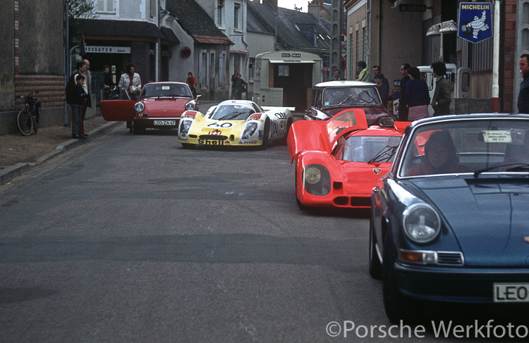 A traffic jam forms outside the Teloché workshop as the #60 Porsche 908 LH of Reinhold Joest/Michel Weber/Mario Casoni leaves for the track