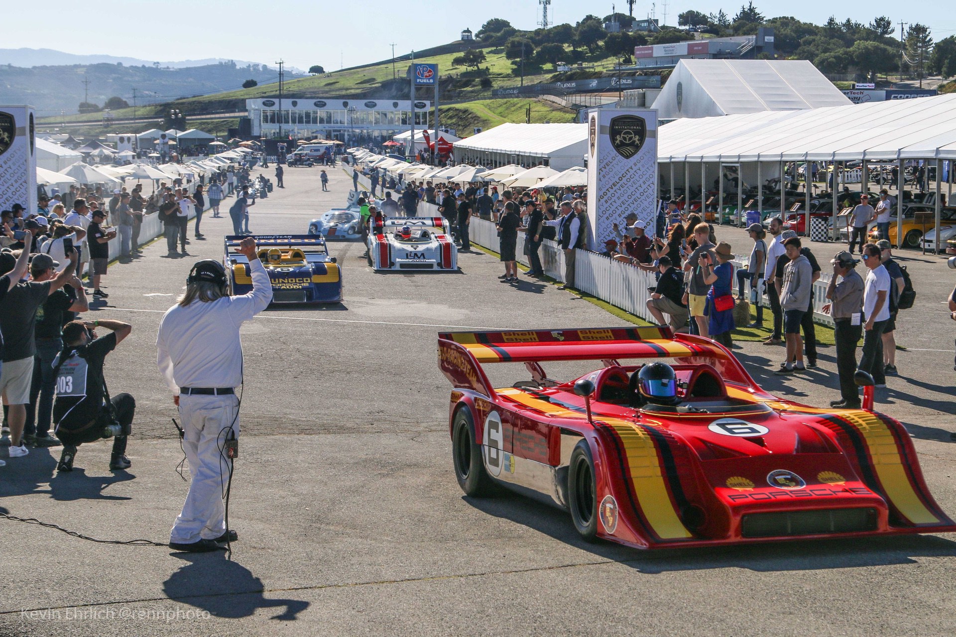 Officials and onlookers near red and yellow Porsche 917 at Velocity Invitational