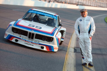 Brian Redman standing next to Porsce on track at Targa Sixty Six