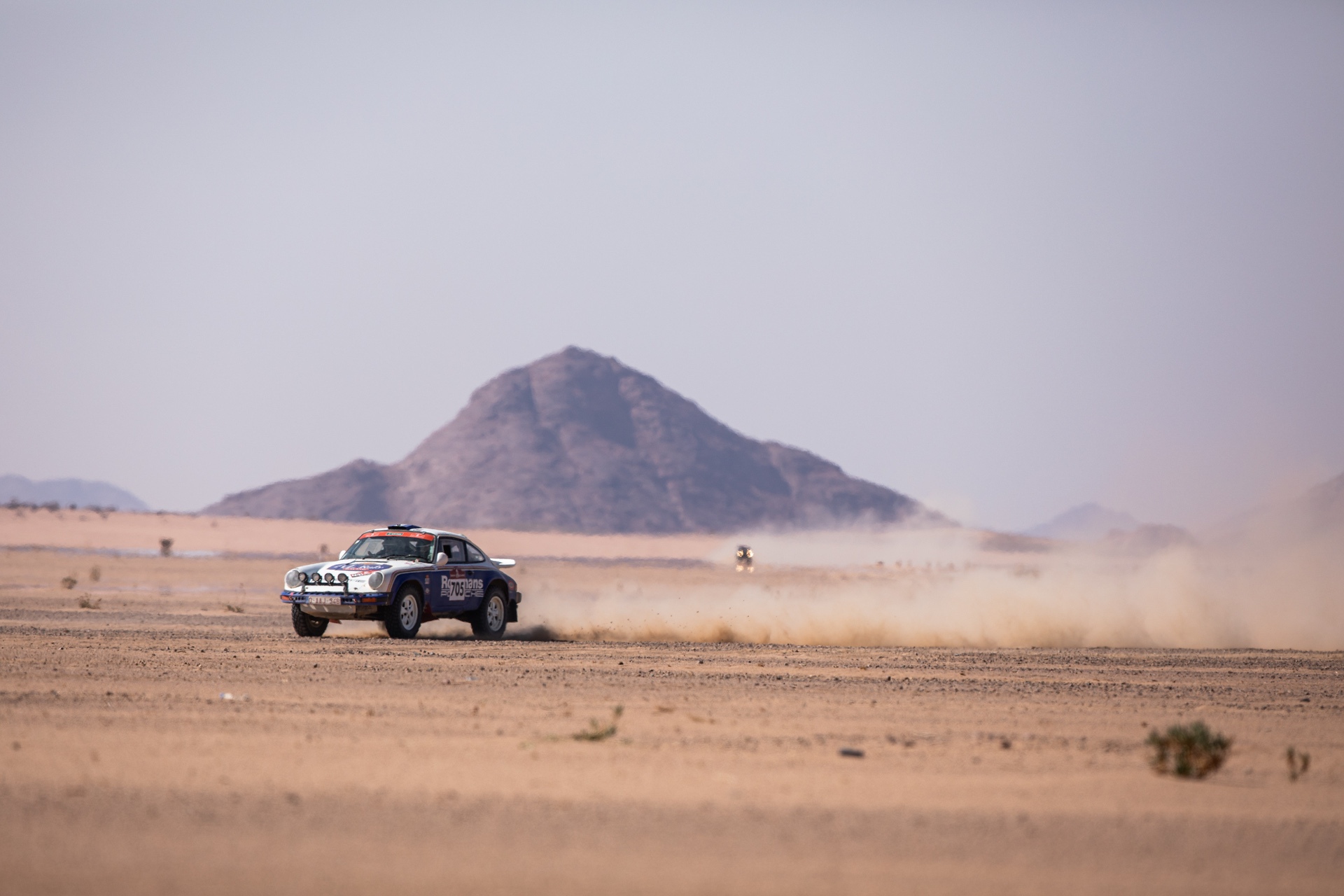 Porsche 911 SC tearing through desert during Dakar Classic