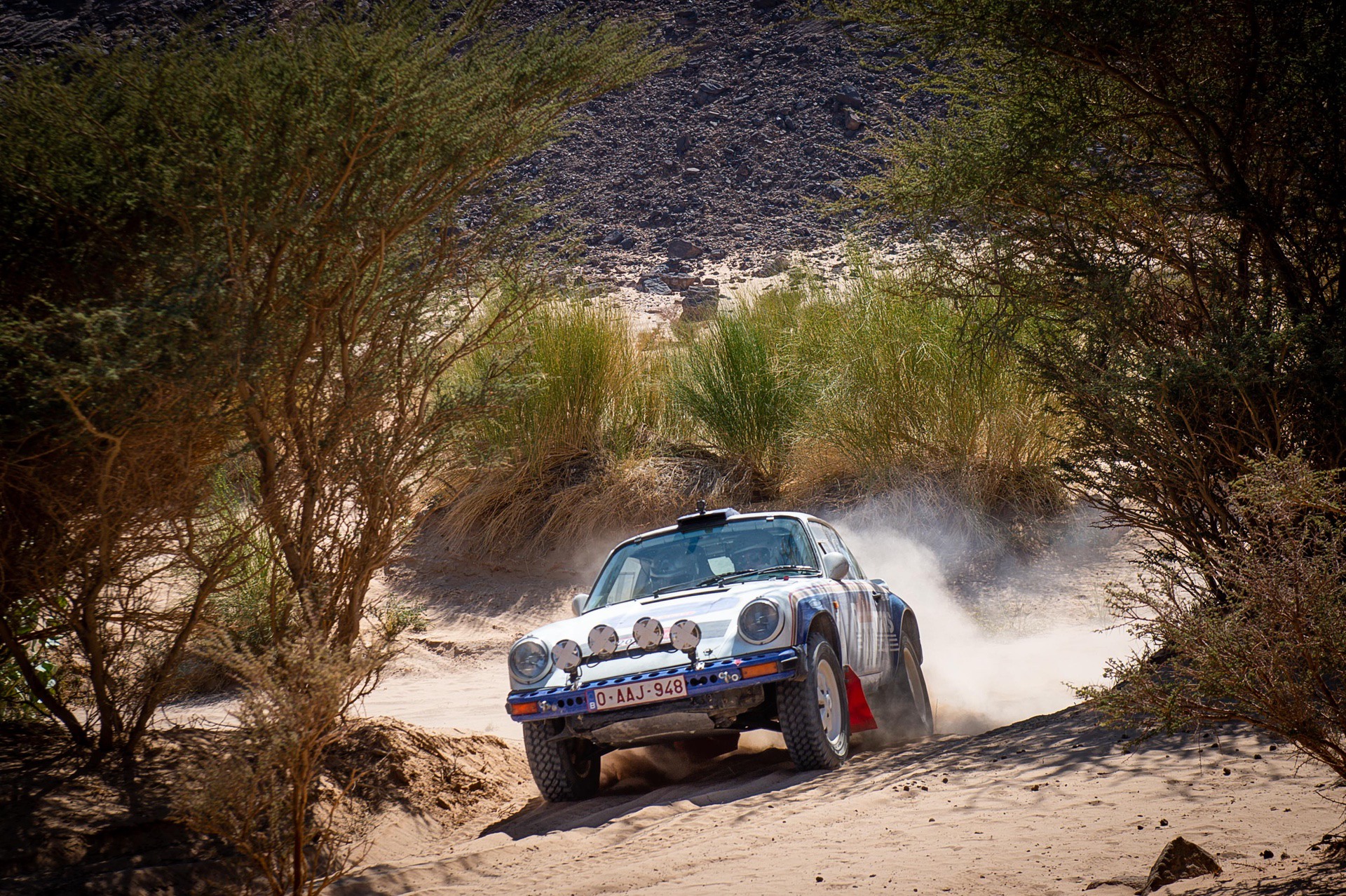 Porsche 911 SC being driven through desert during Dakar Classic