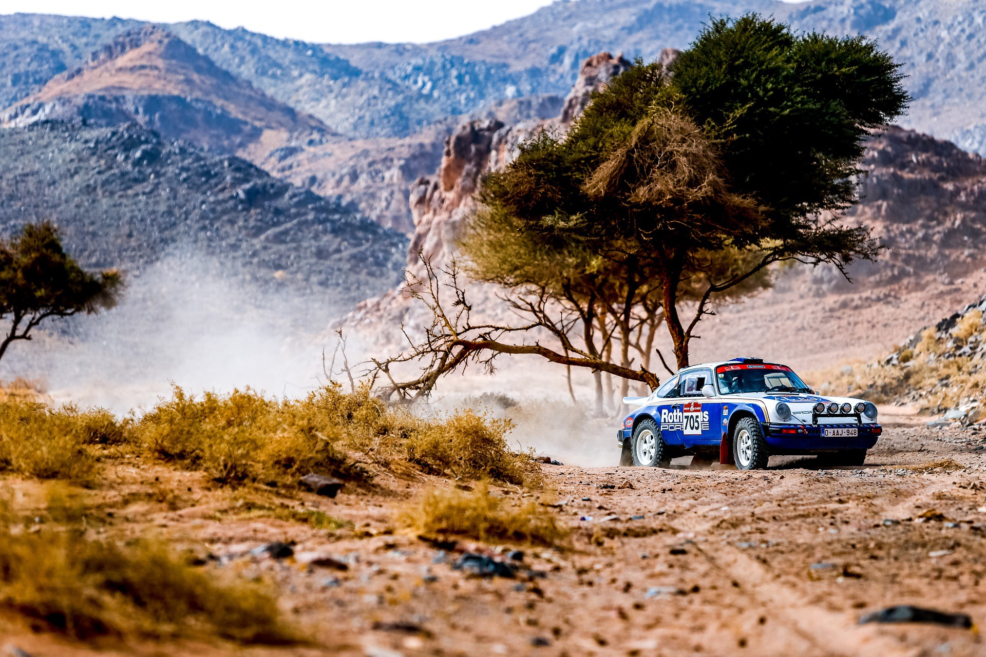 Porsche 911 SC driving through desert at 2022 Dakar Classic