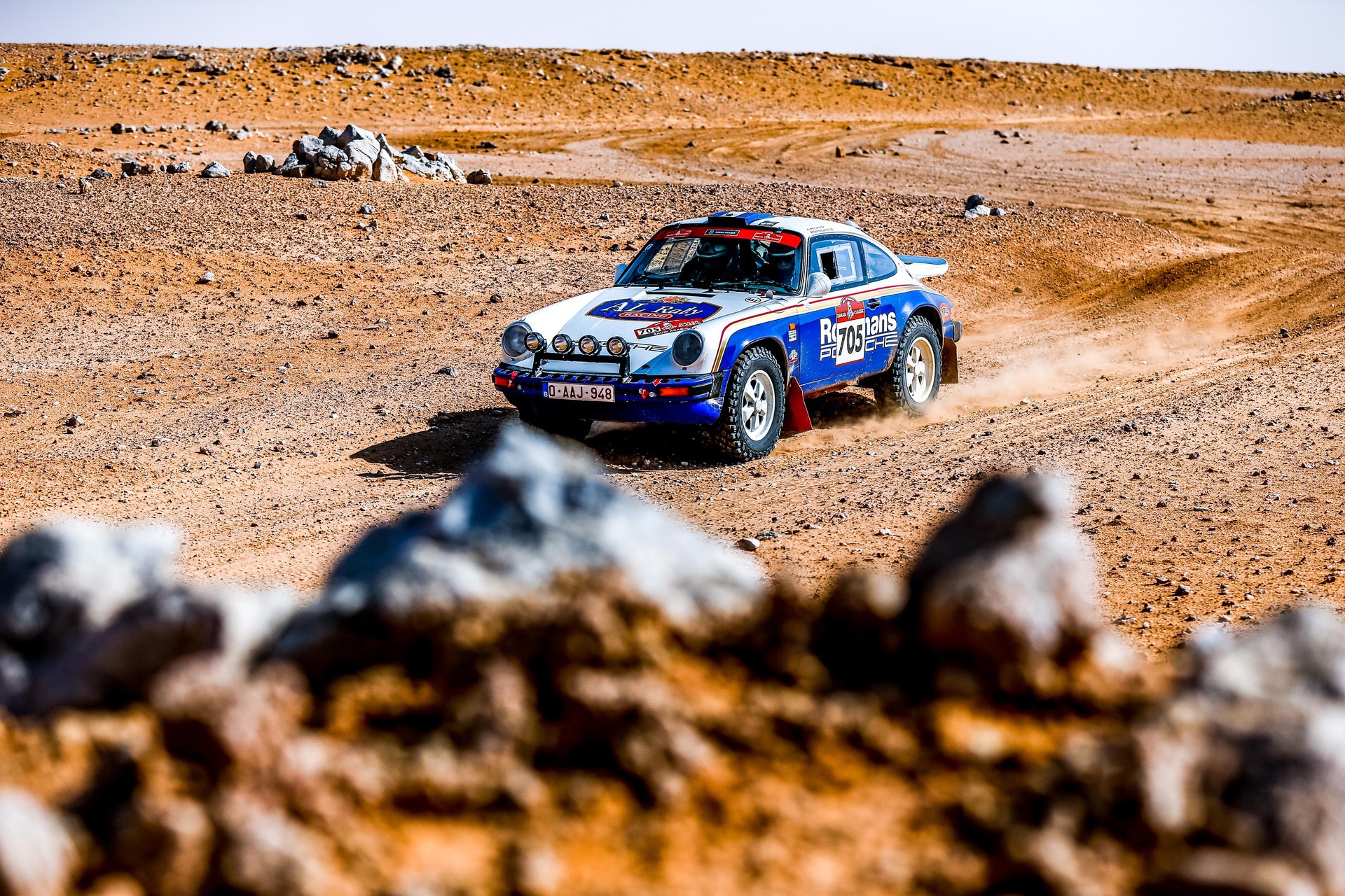 Porsche 911 SC driving through desert during Dakar Classic