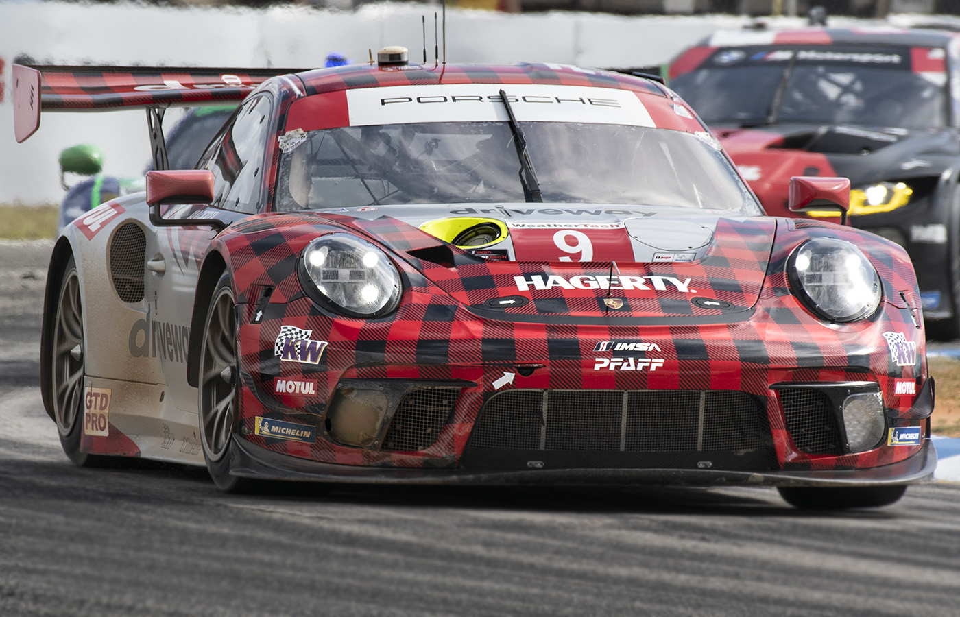 Porsche in red and black plaid livery on track at Sebring 2022