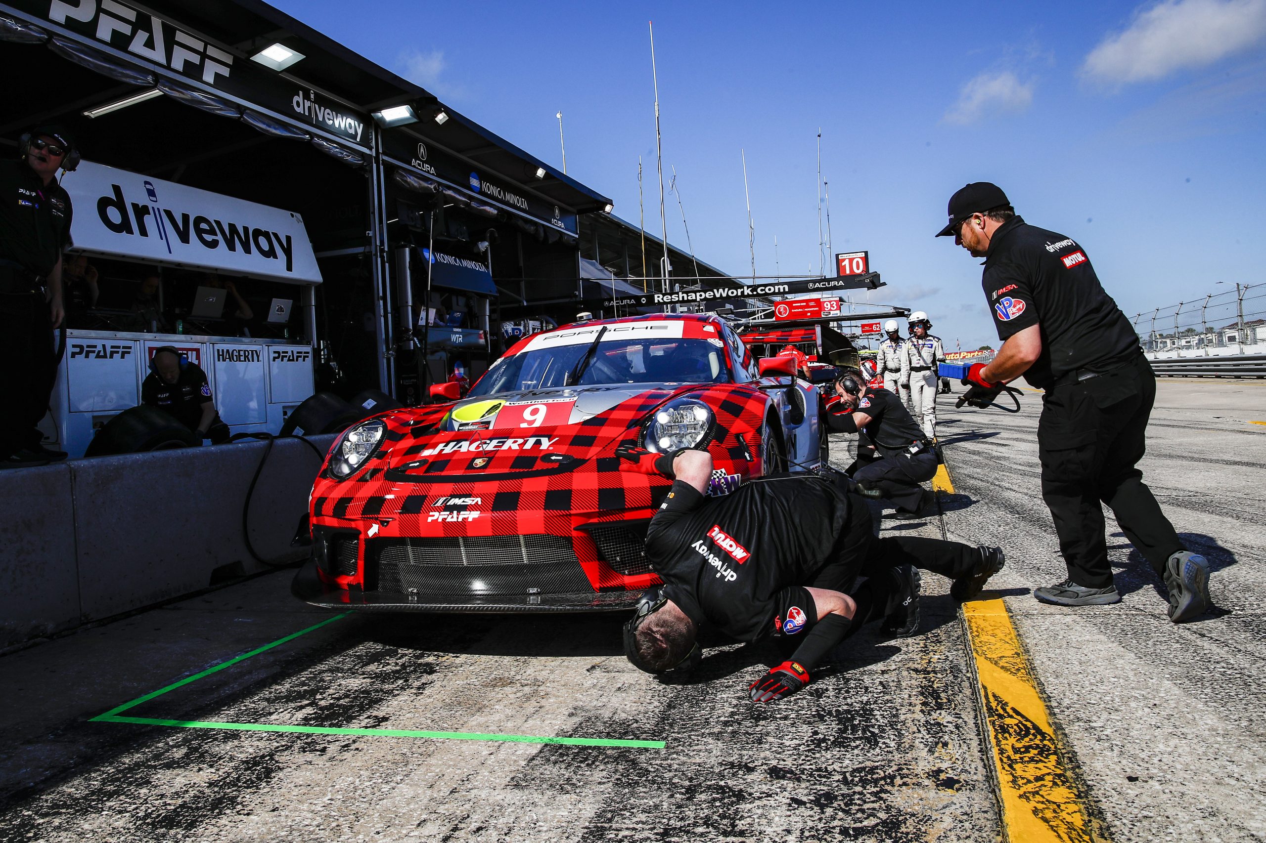 Porsche 911 GT3 R being serviced by pit crew during Sebring 2022
