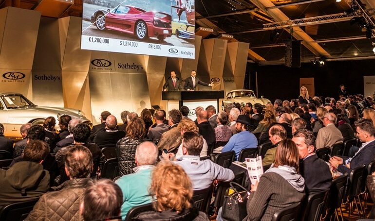 Crowd of people bidding on Porsches at auction