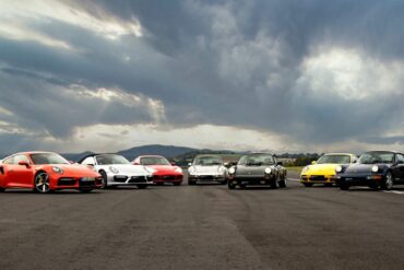 Porsche 911 cars in different colors parked outside on road