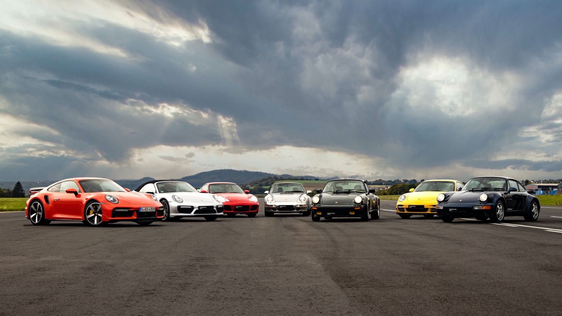 Porsche 911 cars in different colors parked outside on road