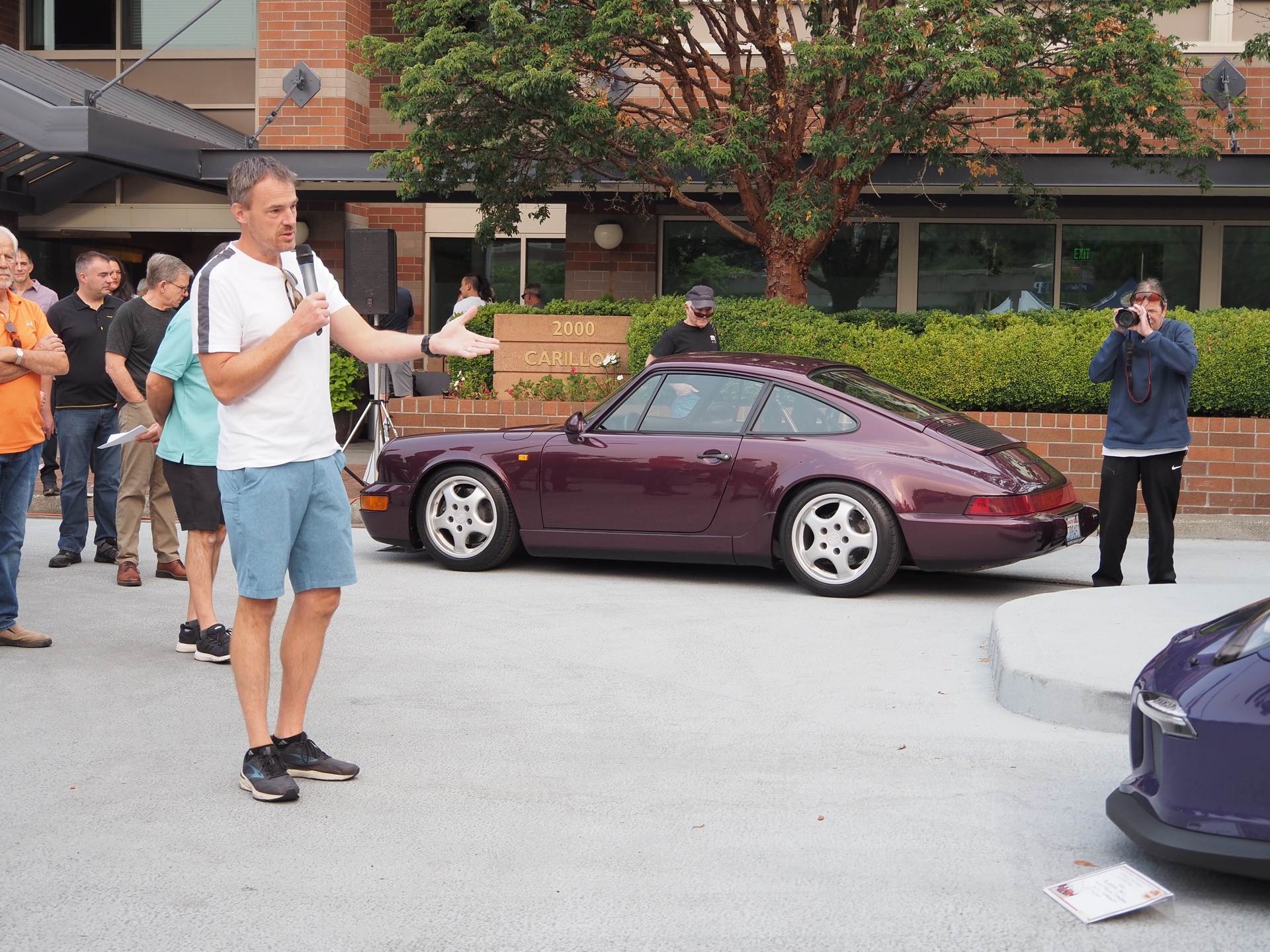 Man with microphone standing near Porsche cars