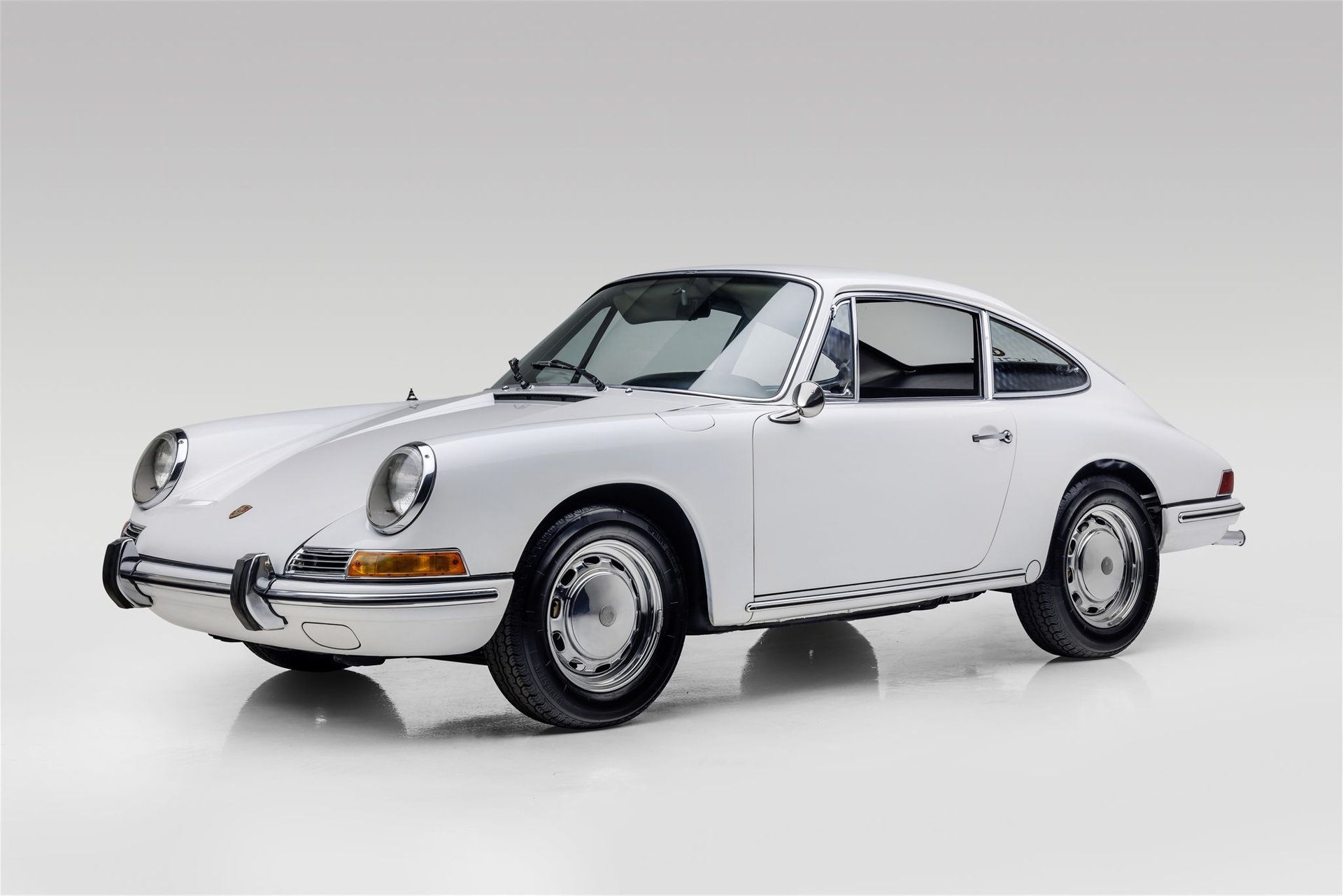 Front-angled view of a white 1965 Porsche 912 against a white background.