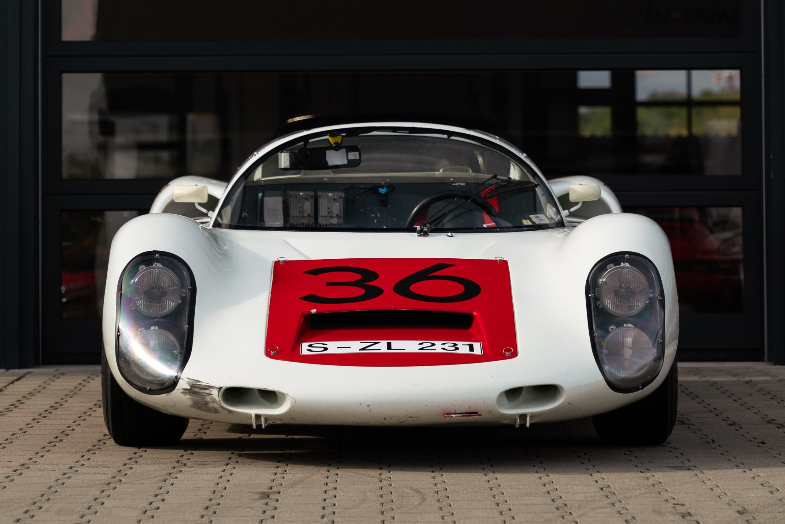 Frontal view of a white and red 1966 Porsche 910 race car.