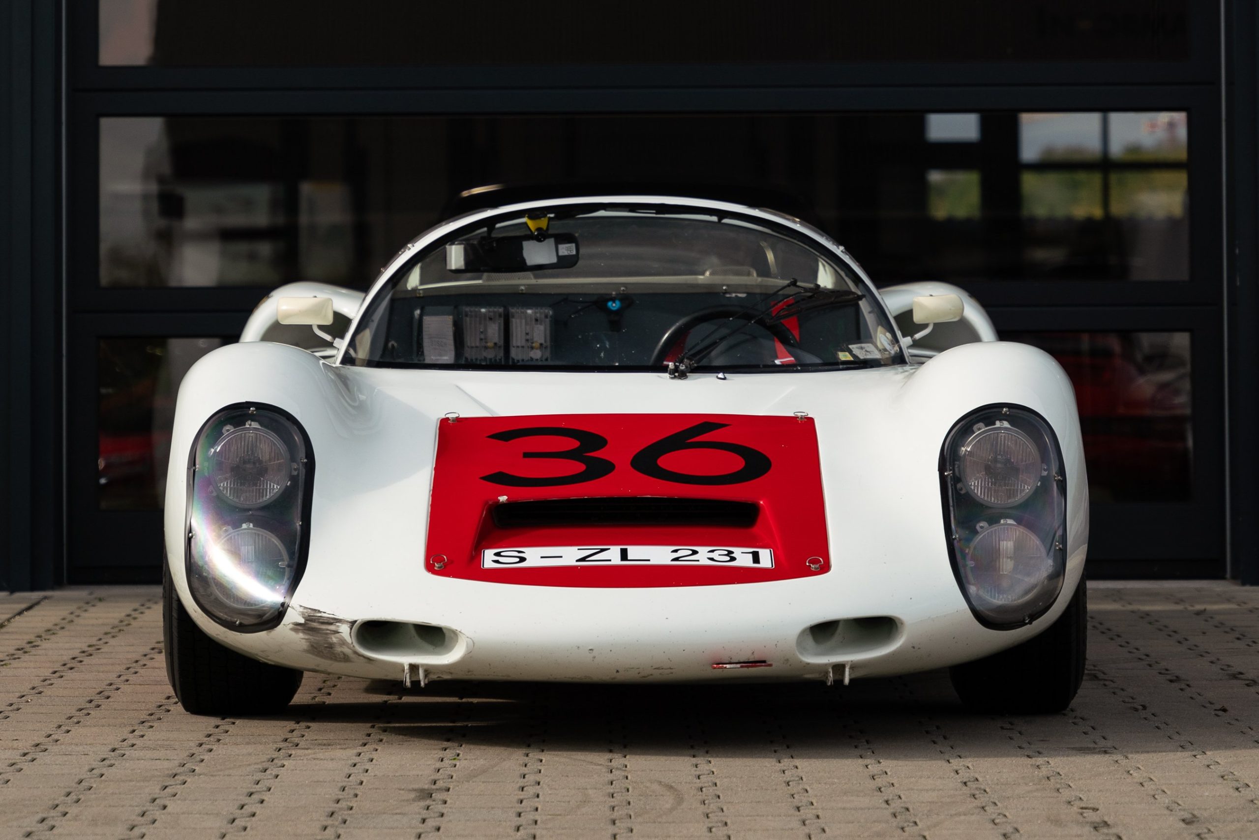 Frontal view of a white and red 1966 Porsche 910 race car.