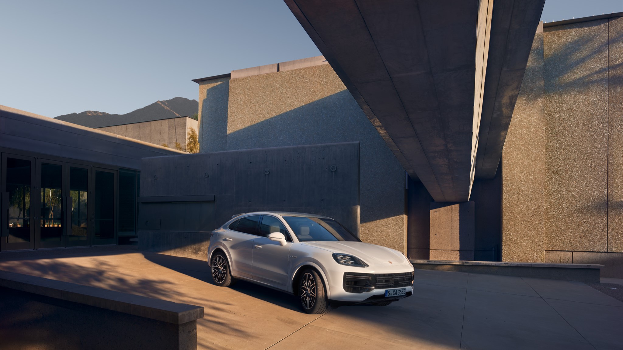 Three-quarter side view of a 2024 white Porsche Cayenne Turbo E-Hybrid Coupe