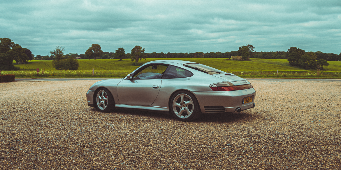 3/4 rear view of a silver 911 996 Porsche in the UK's countryside