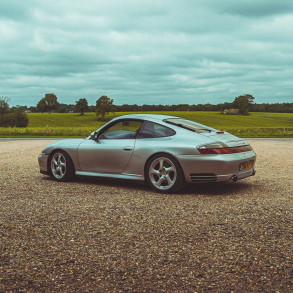 3/4 rear view of a silver 911 996 Porsche in the UK's countryside