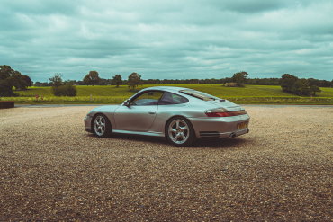 3/4 rear view of a silver 911 996 Porsche in the UK's countryside