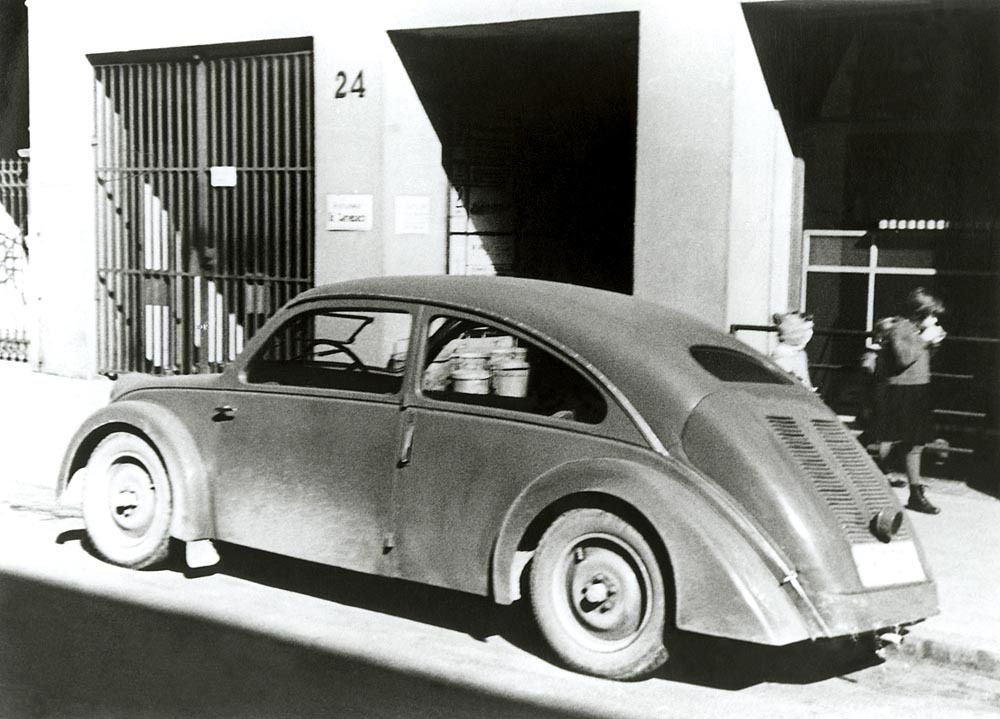 Photographed outside Porsche’s Stuttgart engineering office, the Type 32 shows how closely the young consultancy connected design work with physical testing and client presentation. Rather than existing only as a drawing study, the NSU prototype became a working demonstration of Porsche’s ability to turn a compact-car concept into a complete, roadworthy machine. Its presence at the firm’s headquarters also reflects the growing importance of outside commissions to the office, which depended on projects like this to build experience, reputation, and commercial credibility during the early 1930s.