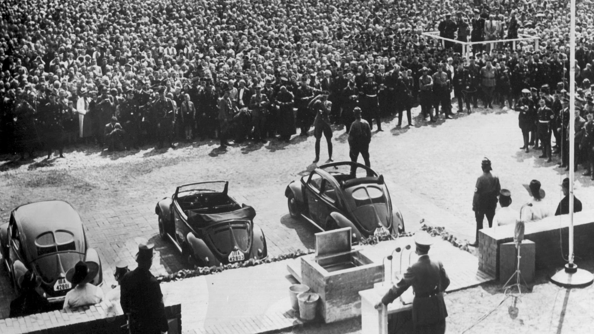 The public unveiling of the early KdF-Wagen presented the automobile as far more than the product of Ferdinand Porsche’s engineering office. Displayed before large crowds and surrounded by the visual language of the Nazi state, the car became part of a carefully staged political spectacle linking technological progress with the authority of the regime and the German Labour Front. These events were designed to make the Volkswagen appear both modern and attainable, reinforcing the promise that ordinary German families would soon gain access to personal mobility. In practice, the ceremonies revealed how thoroughly the project had been absorbed into the state’s propaganda machinery.